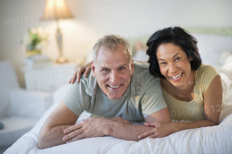 Happy mature couple laying in bed.