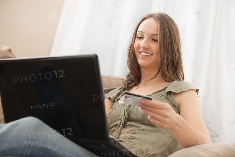 Young woman using laptop and holding credit card. Photo : Mike Kemp