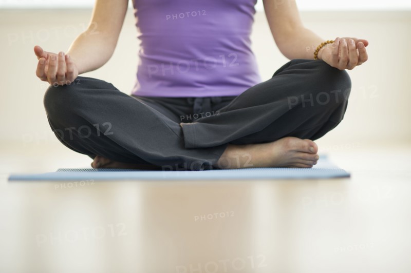 Young woman meditation in lotus position, low section.