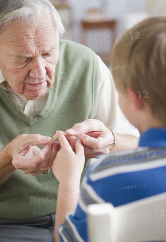 Grandfather stocking Band-Aid to grandson's (8-9) finger. Photo : Jamie Grill Photography