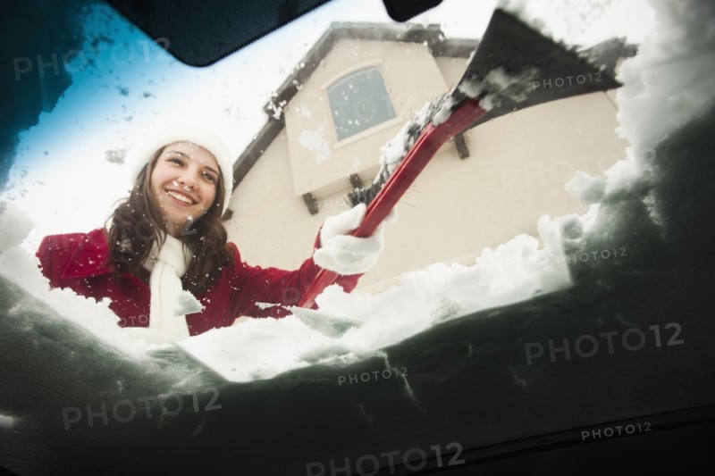 USA, Utah, Lehi, Young woman scraping snow from car windscreen. Photo : Mike Kemp