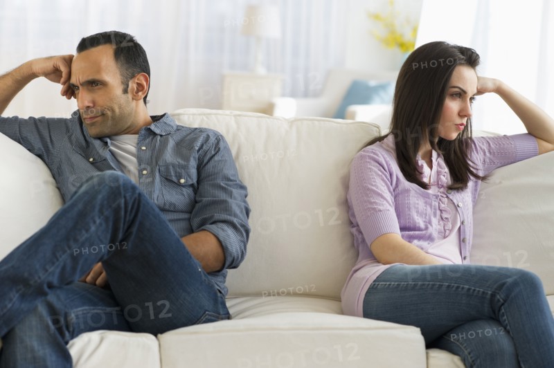 Couple sitting on sofa back to back.