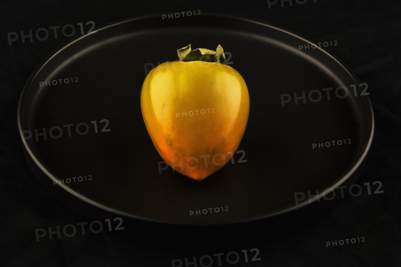 Persimmon on black background. Photo : Joe Clark