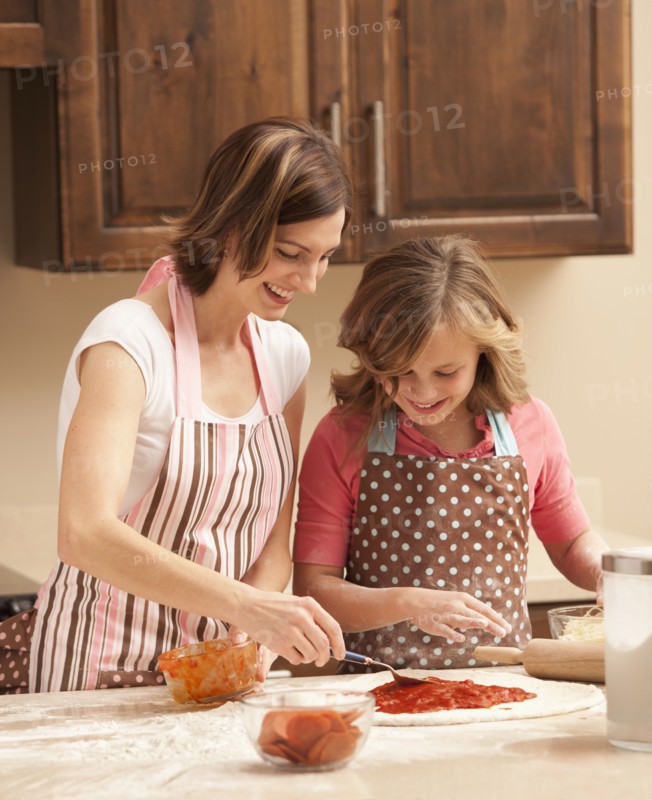 Mother and daughter (10-11) preparing pizza in kitchen. Photo : Mike Kemp
