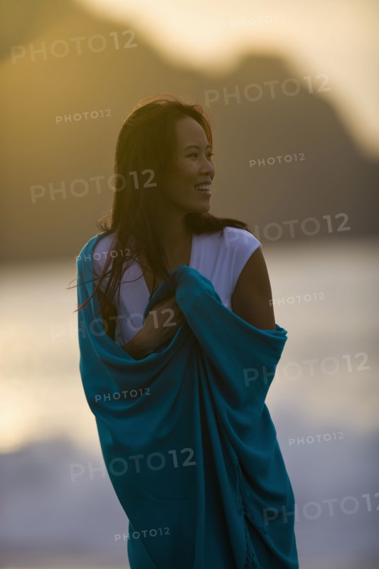 USA, California, San Francisco, Young woman wrapped in blanket at coast. Photo : Noah Clayton