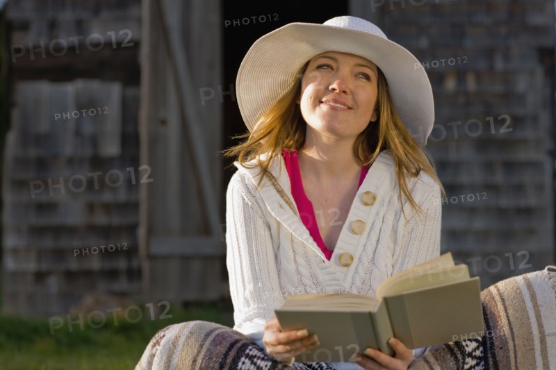 USA, California, Bolinas, Young woman reading book outdoors. Photo : Noah Clayton