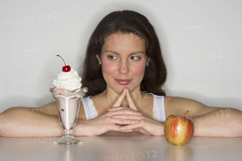 Woman choosing between ice cream and apple.