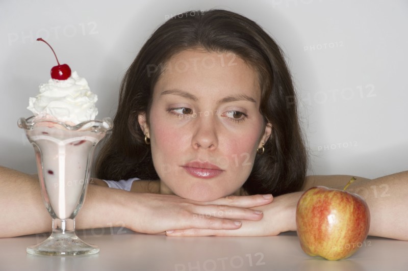 Woman choosing between ice cream and apple.