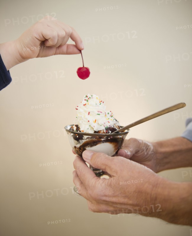 Close up of hands of grandfather and grandson (8-9) holding icecreame and cherry. Photo : Jamie Grill Photography