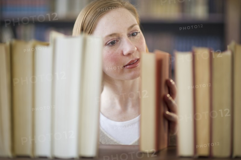 Woman looking for book in library.