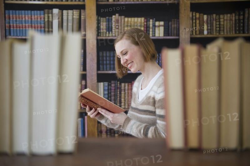 Woman reading book in library.