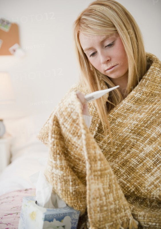 Woman wrapped in blanket measuring temperature. Photo: Jamie Grill Photography