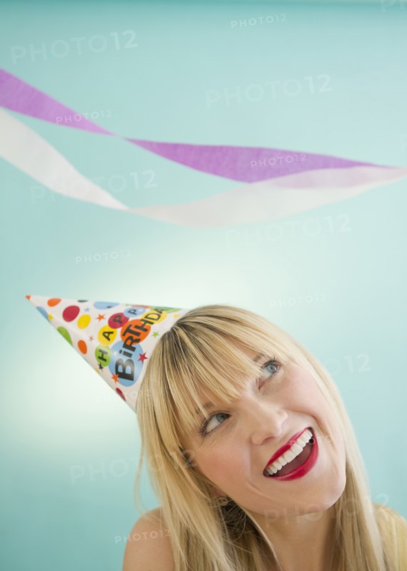 Young woman wearing party hat laughing. Photo: Jamie Grill Photography