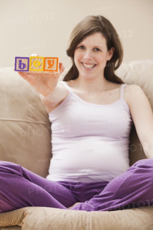 Young pregnant woman holding plastic letters reading: 'boy'. Photo : Mike Kemp