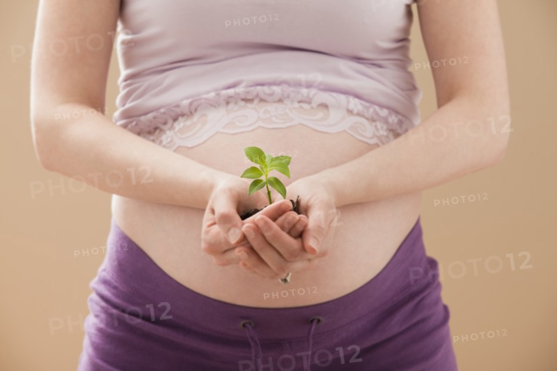 Young pregnant woman holding young plant. Photo : Mike Kemp