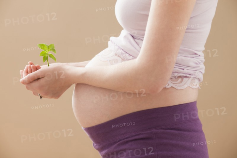 Young pregnant woman holding young plant. Photo: Mike Kemp