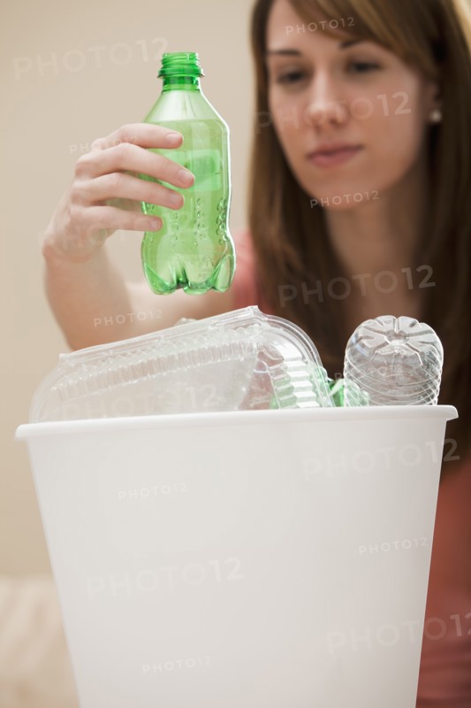 Studio shot of woman (8-9) placing plastic bottle in recycling bin. Photo: Mike Kemp