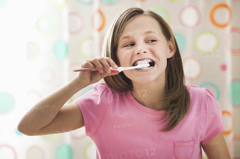 Girl (10-11) brushing teeth. Photo : Mike Kemp