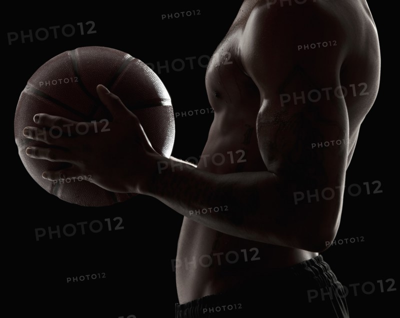 Studio shot of shirtless man holding basketball, mid section. Photo: Mike Kemp