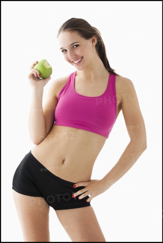 Studio portrait of young woman eating apple. Photo: Mike Kemp