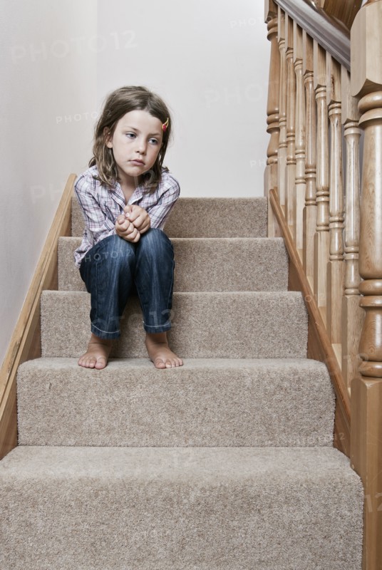 Girl (8-9) sitting on stairs. Photo : Justin Paget