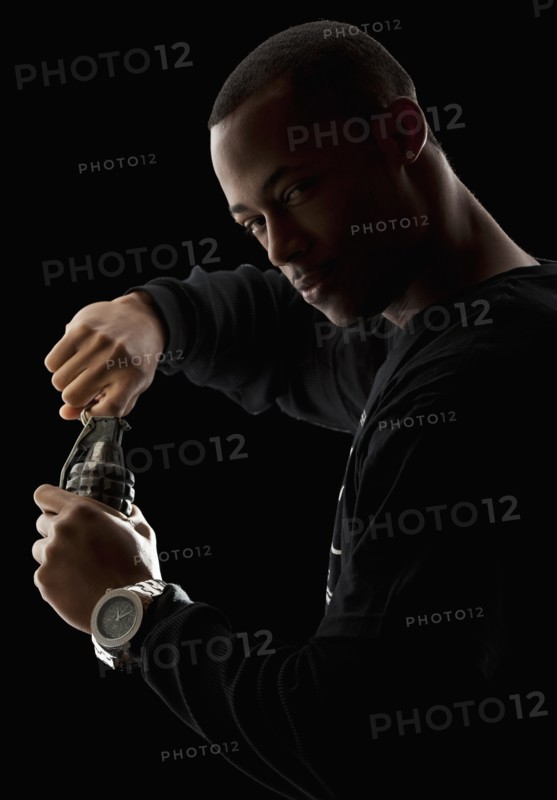Studio portrait of young man holding grenade. Photo : Mike Kemp