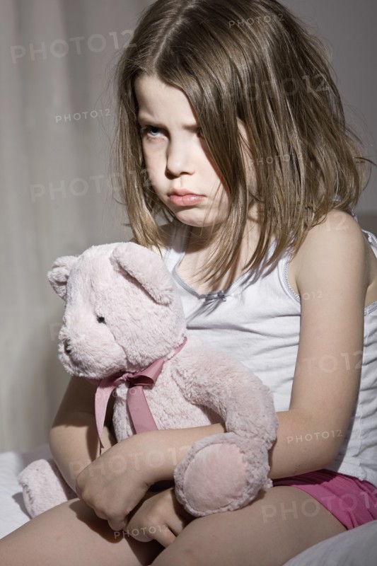 Studio portrait of sad girl (6-7) with pink teddy bear. Photo : Justin Paget