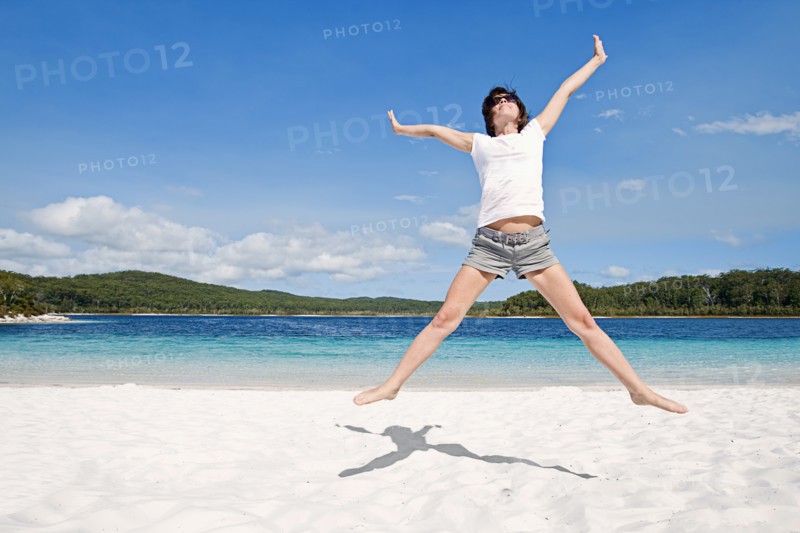 Fraser Island, Australia, Woman cheering on beach. Photo : Justin Paget