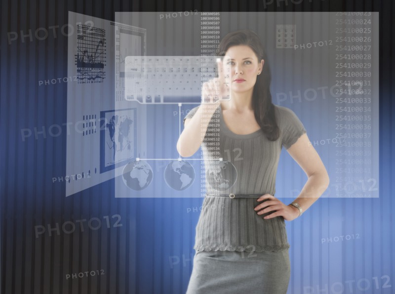 Woman in futuristic office touching computer panel.