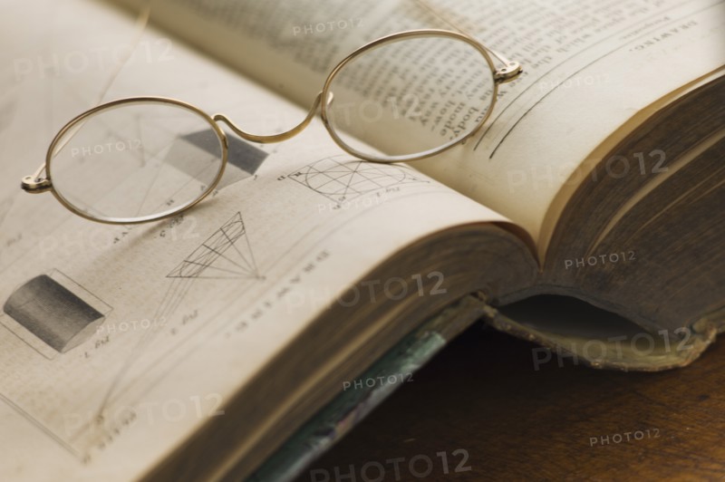 Close up of antique glasses lying on open book.