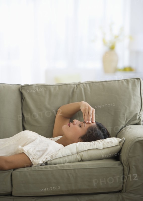 Woman lying on sofa with headache.