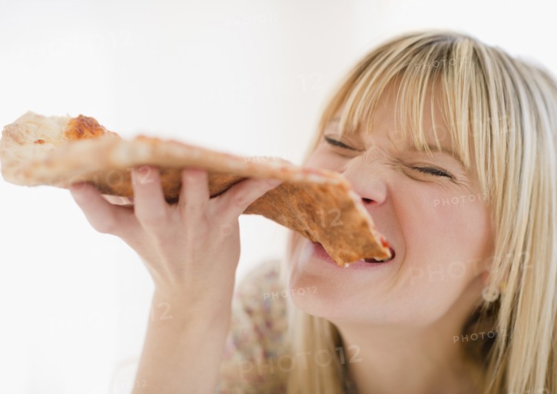 Young woman eating pizza. Photo: Jamie Grill Photography