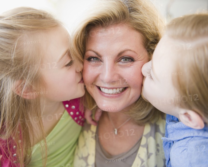 Daughters (8-11) kissing mother. Photo : Jamie Grill Photography