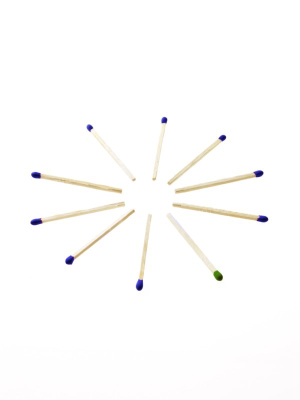 Blue matches with one green on white background. Photo: David Arky