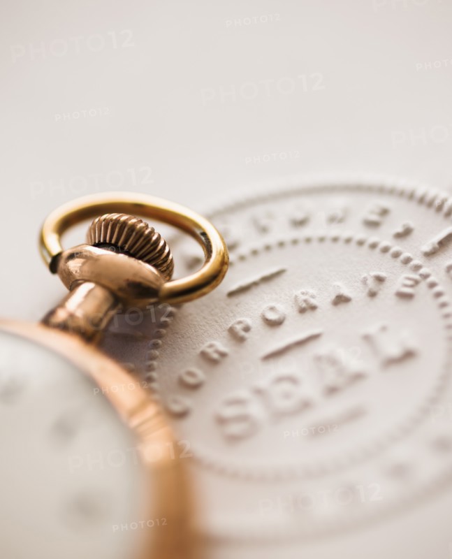 Close up of pocket watch and corporate seal.