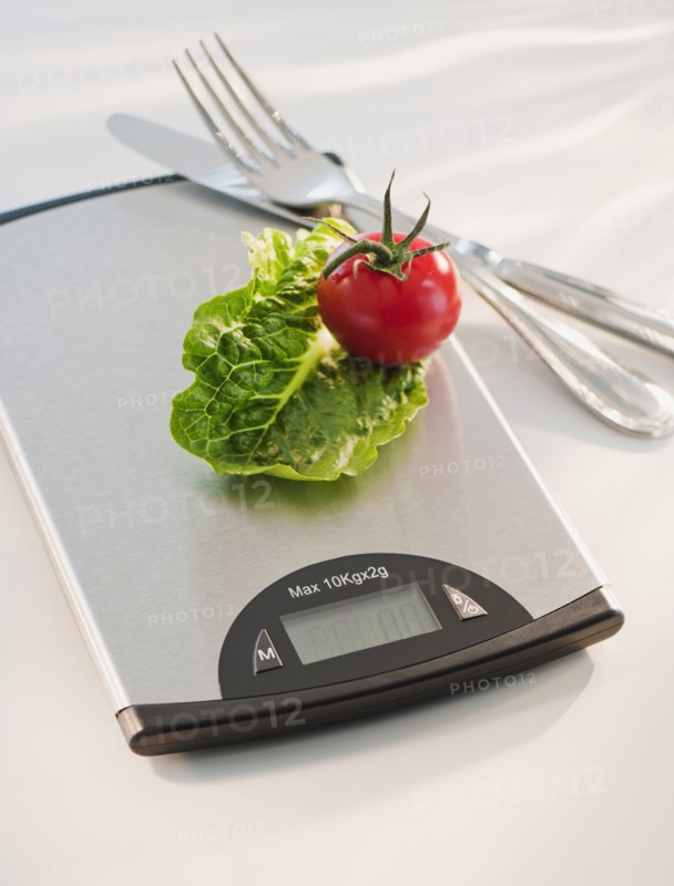 Lettuce and tomato on weight scale.