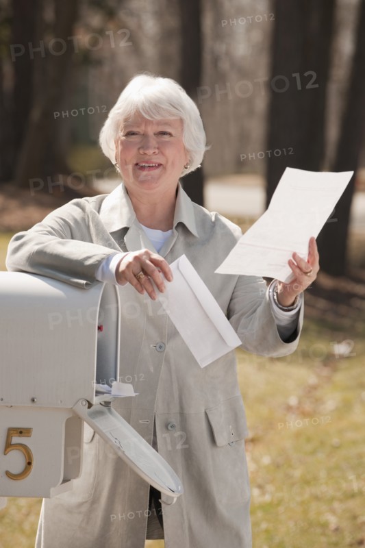 USA, Virginia, Richmond, senior woman reading letters by mailbox. Photo: Mark Edward Atkinson