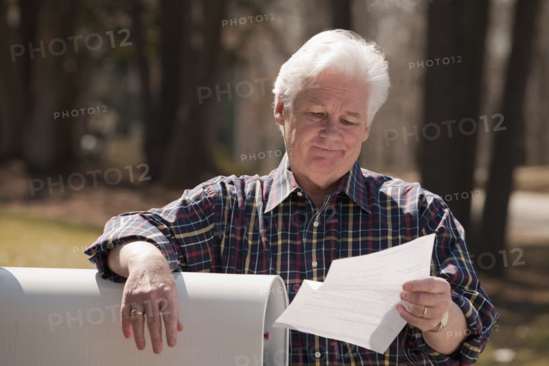 USA, Virginia, Richmond, senior man reading letter by mailbox. Photo: Mark Edward Atkinson