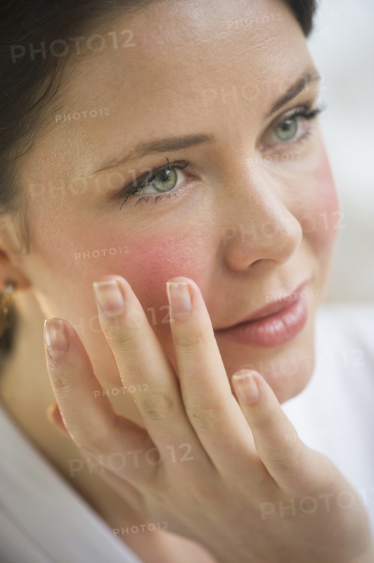 Woman applying cosmetics on face.