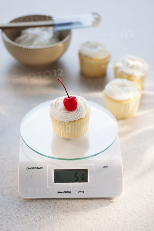Studio shot of cupcake on weight scale.