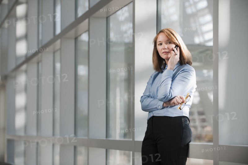 Businesswoman talking on phone in corridor. Photo : Mark Edward Atkinson