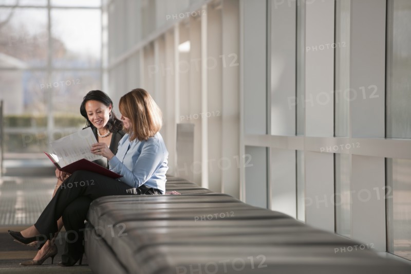 Businesswomen talking in corridor. Photo: Mark Edward Atkinson