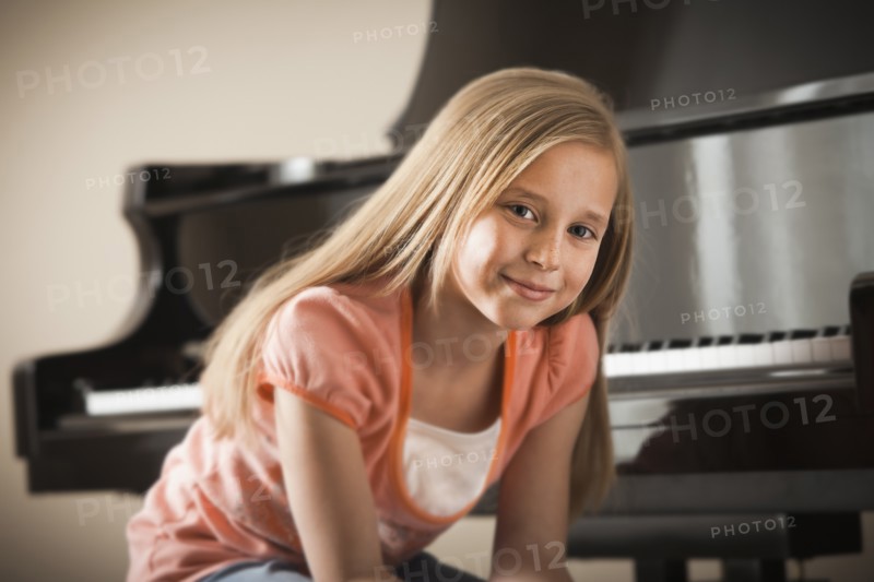 Portrait of girl (8-9) sitting by piano. Photo: Mike Kemp