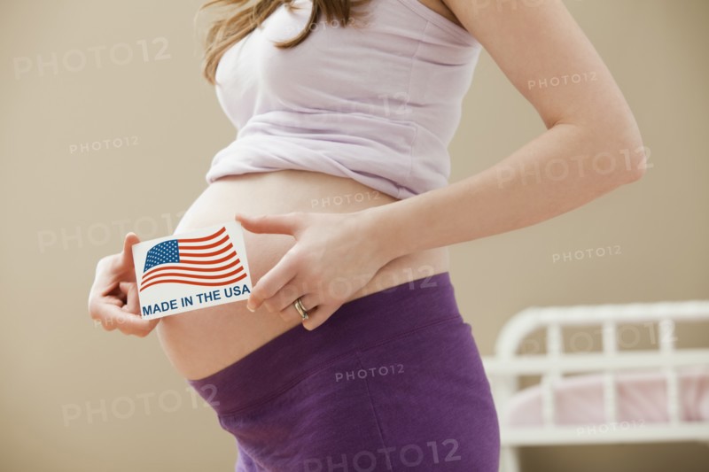 Young pregnant woman holding Made in the USA Sign. Photo: Mike Kemp