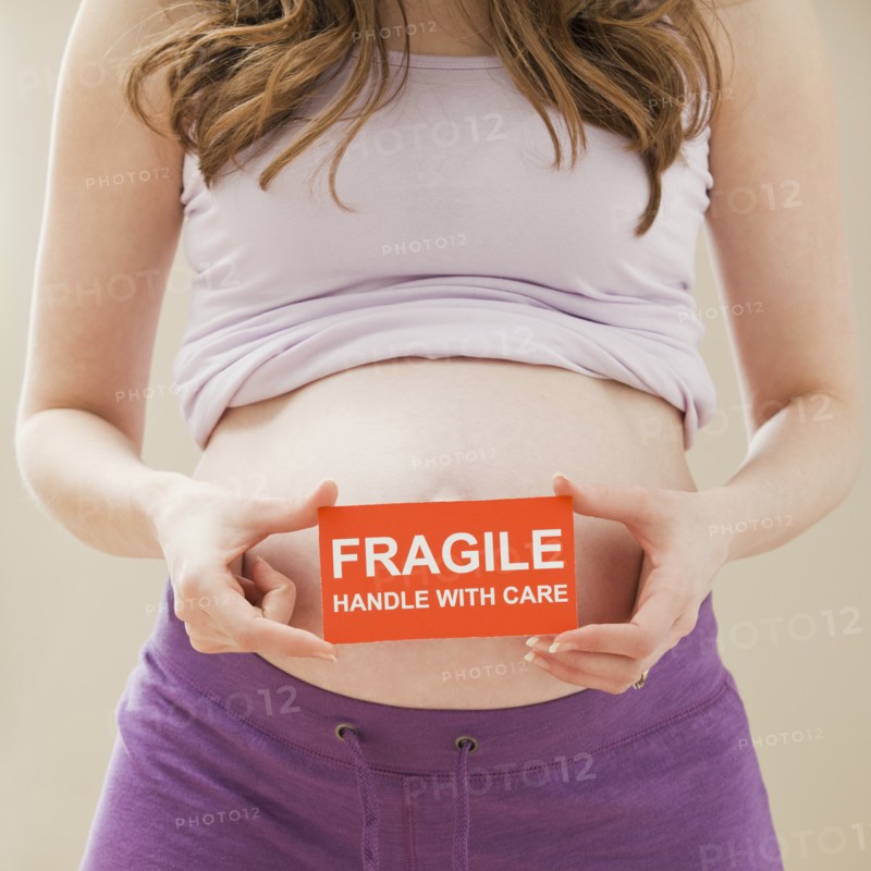 Young pregnant woman holding fragile sign. Photo: Mike Kemp