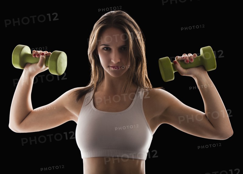 Studio portrait of young woman using hand weights. Photo: Mike Kemp
