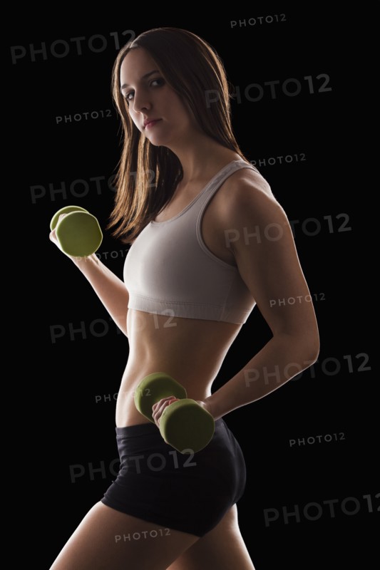 Studio portrait of young woman using hand weights. Photo : Mike Kemp