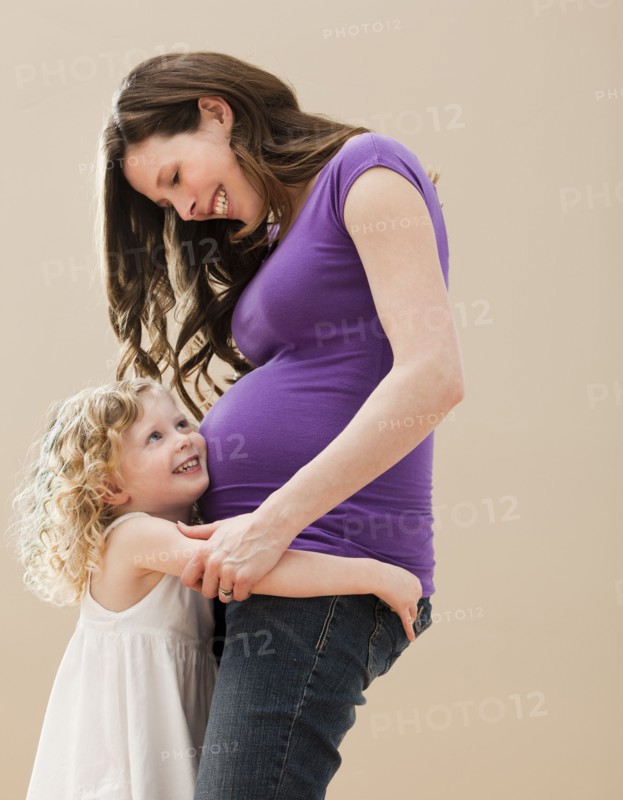 Portrait of girl (2-3) and pregnant mother embracing. Photo: Mike Kemp