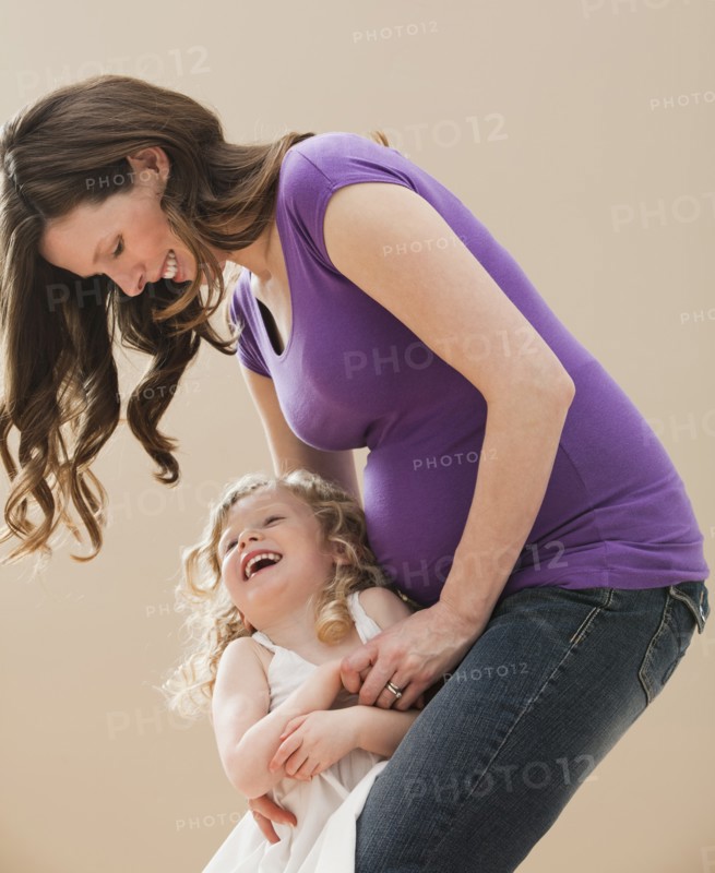 Portrait of girl (2-3) and pregnant mother embracing. Photo: Mike Kemp