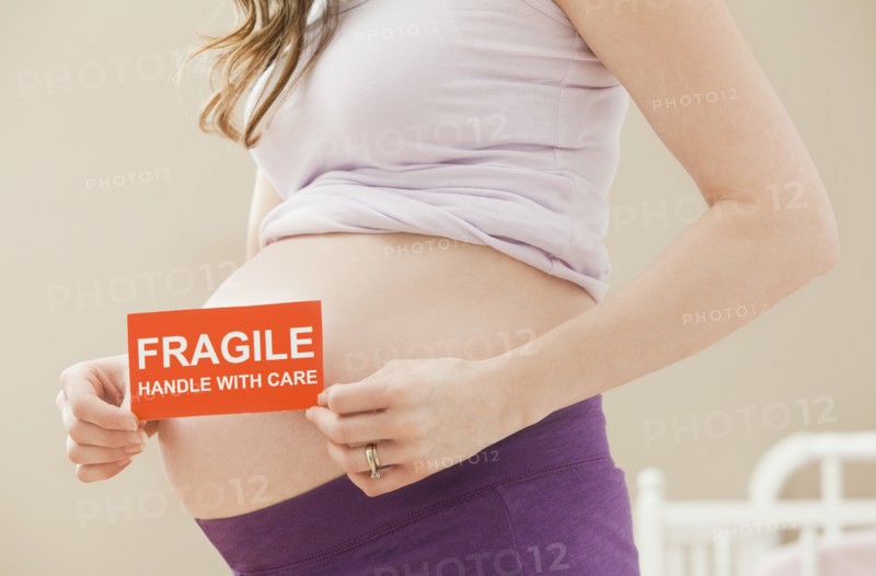 Young pregnant woman holding fragile sign. Photo: Mike Kemp